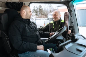 doradztwo-transportowe-kierowca-ciezarowki Doradca transportowy rozmawiający z kierowcą ciężarówki w kabinie pojazdu